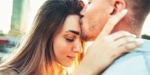 man kissing woman on forehead
