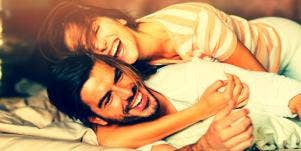 couple smiling and laughing holding each other in bed