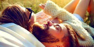 couple laying in the grass together while boyfriend is being distant