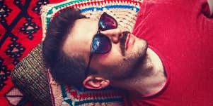 handsome man with mustache and sunglasses reclines on blanket