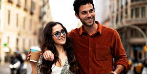 brown-haired man and woman walk down a street