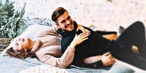 man and woman laughing in bed, wearing sweaters