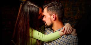 woman kissing man sitting on his lap