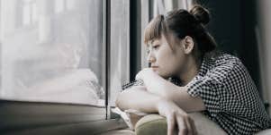 lonely woman looking out a window