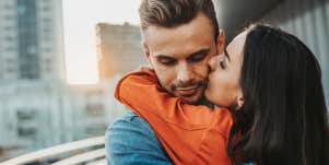 couple cuddles on a balcony in a city