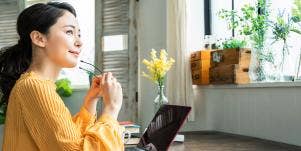 woman putting on glasses in front of laptop