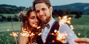 man and woman in wedding clothes holding sparklers 