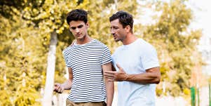father walking with teen son, talking seriously but kindly 