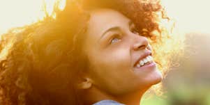 Young woman smiling and looking toward the sky.