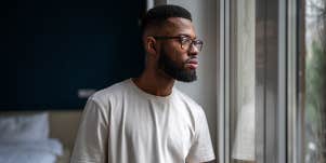 man looking out window in thought