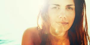 Woman looking hopeful with a sun flare behind her
