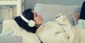 woman laying on couch listening to music