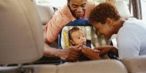 parents buckling a baby into a car seat