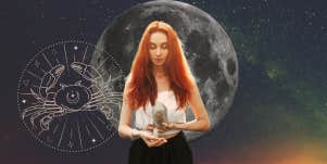 woman holding crystals for cancer zodiac sign in front of moon