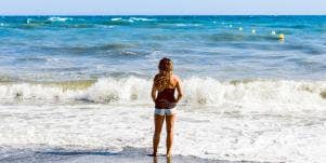 Girl standing facing water