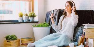 woman wearing headphones covered in blanket at home