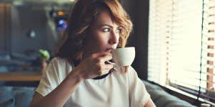 woman pensively sipping coffee in a fancy diner