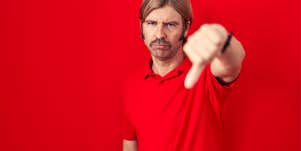 man in his 40s standing in front of red background