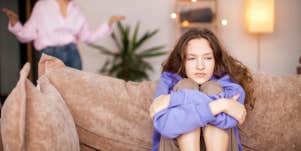 Girl sitting on couch being disciplined by parent 