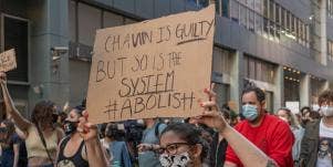 Woman holding sign that says Chauvin is guilty, but so is the system
