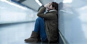 woman with head in hands against wall