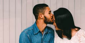 man kissing woman's head