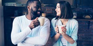 guy and girl looking at each other smiling while holding coffee mugs