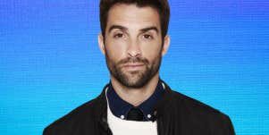 man looking into the camera in front of blue background