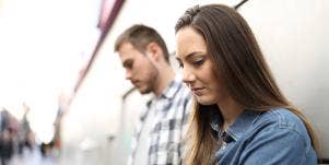 sad looking woman leaning on wall next to man