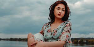 woman sitting alone by lake on a cloudy day