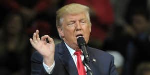 donald trump at a microphone, making a weird gesture