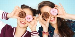 two girls holding donuts up to their eyes
