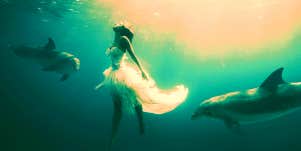 woman dreaming about being under water surrounded by dolphins