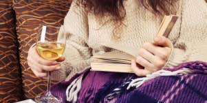 woman having a glass of wine and reading