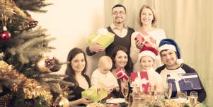 family perfectly posed by Christmas tree with gifts