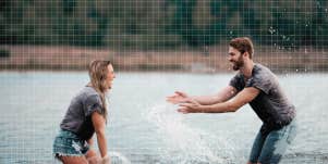 Couple being playful at the lake, splashing each other