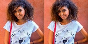 young Black woman smiles at the camera on an orange background