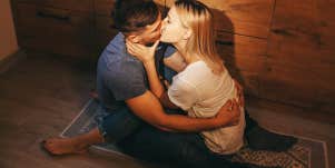 couple sitting on floor in the kitchen and kissing each other