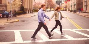 man holding woman's hand crossing the street
