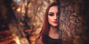 woman standing behind a tree