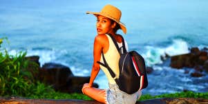 woman sitting on cliff edge overlooking ocean