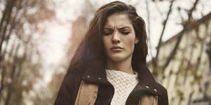 long-haired brunette woman looking upset in the woods, sepia-toned
