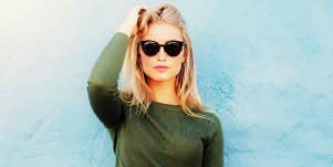 blonde woman in sunglasses against a light blue wall