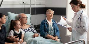 family sitting around man in hospital bed