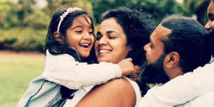 Dad, mom and young daughter hugging while laughing and talking