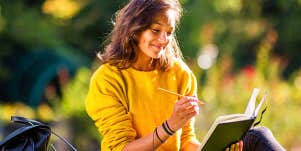 Woman outdoors writes in journal