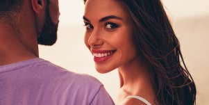 Woman smile and looks over her shoulder next to man.