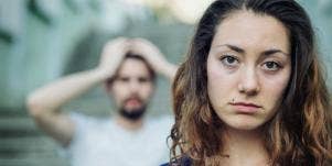 man looking exasperated behind woman looking solemn