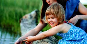 little girl playing in stream with mother 