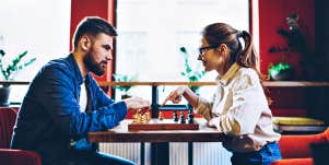 Couple playing chess in a red room with big windows